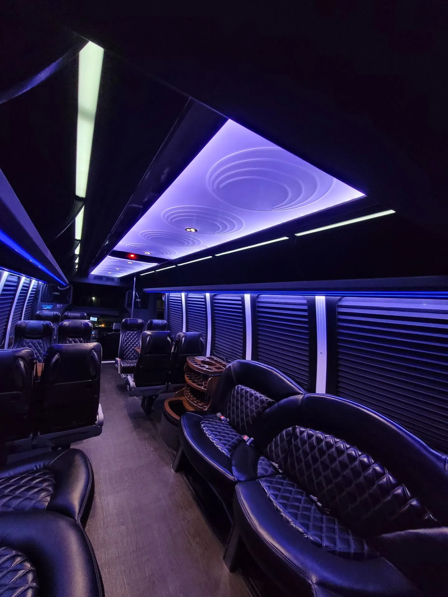 Charter bus interior with leather seats and soft purple ambient lighting